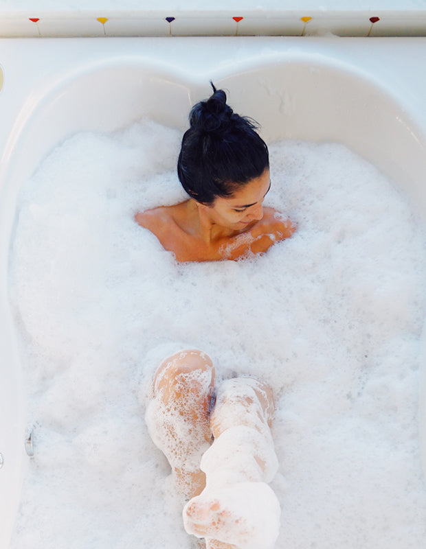 woman in bath covered in white bubbles