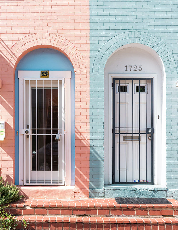 two home doors side-by-side with brightly painted brick, pink and blue