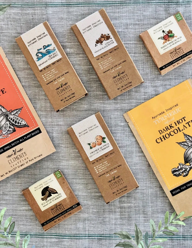 raw chocolate products from Elements Truffles are laid neatly on a cloth with green plants scattered around