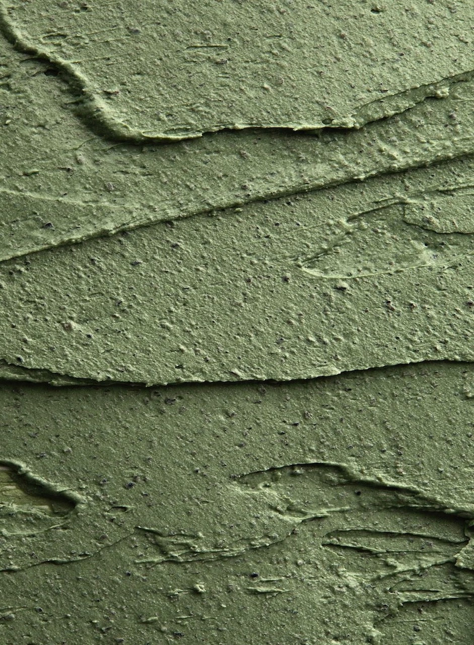 A thick swatch of green clay mask, spread and peaked across the frame
