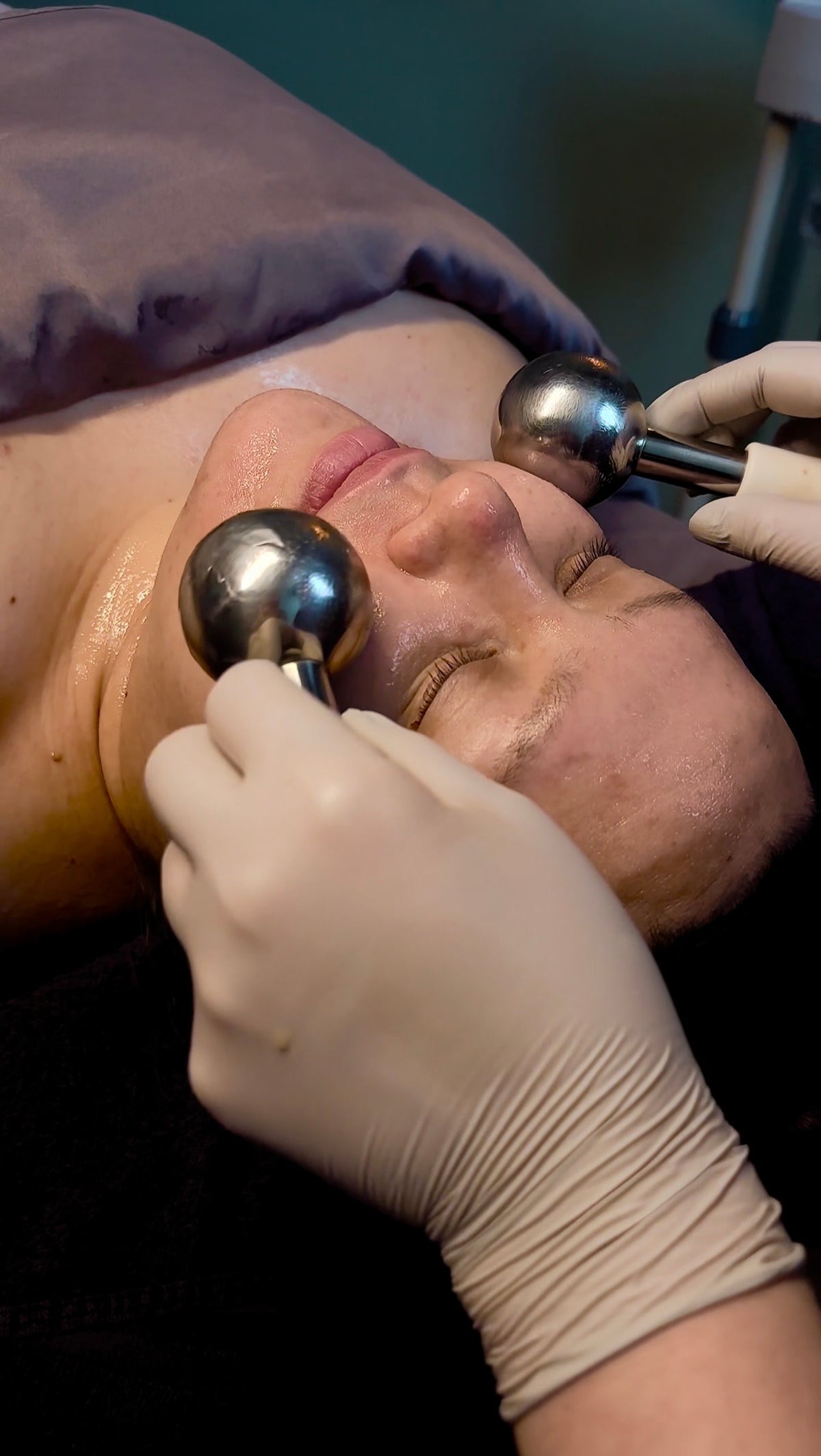 An esthetician glides two chrome ice globes over a client's face during a facial at Lena Rose.